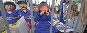  ?? – AFP ?? CALL FOR REMOVAL: A protester wearing a mask of South Korea’s impeached President Park GeunHye sits in a mock prison during a rally calling for Park’s immediate removal in downtown Seoul on Saturday.