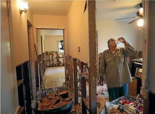  ?? REUTERS ?? Rogelio Salina takes a break as he helps a neighbour clean a house damaged by floodwater­s from Hurricane Harvey in East Houston, Texas yesterday.