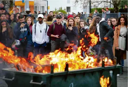  ?? Bob Edme/Associated Press ?? Estudantes observam lixo incendiado durante protesto diante de sua escola em Bayonne, na França
