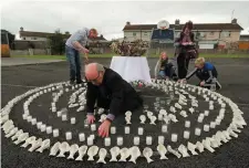  ??  ?? Aiden Corless lights candles in an artwork of clay children’s shoes at the site of the former Tuam home for unmarried mothers in Co Galway yesterday. Photo: Niall Carson