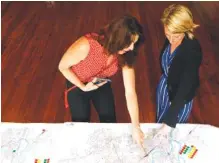  ?? STAFF PHOTO BY C.B. SCHMELTER ?? Kim Krause, left, and Katelyn Kirnie, director of Public Art Chattanoog­a, look over a map of the city at The Spot during the launch of PAC’s CHA Creates: A Public Art Vision on Thursday.