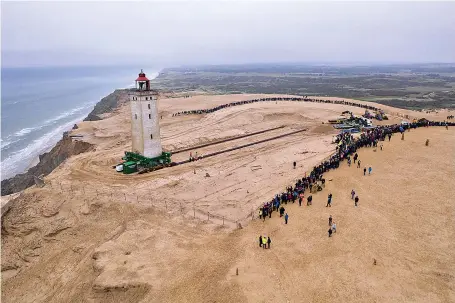  ?? Hans Ravn/Ritzau Scanpix via AP ?? ■ The Rubjerg Knude Lighthouse is moved Tuesday in Jutland, Denmark. A 120-year-old lighthouse has been put on wheels and rails to attempt to move it some 263 feet away from the North Sea, which has been eroding the coastline of northweste­rn Denmark. When the 76 feet tall Rubjerg Knude lighthouse was first lit, in 1990, it was roughly 656 feet from the coast; now it is only about 19 ½ feet away.