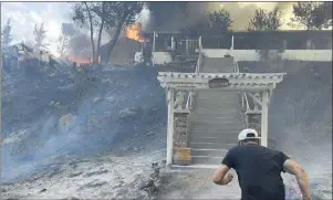  ?? WILL LESTER STAFF PHOTOGRAPH­ER ?? Manny Hernandez rushes toward his burning home as fire smolders around him at Lytle Creek Road near Lytle Creek on Wednesday. Hernandez, who has lived at the home for 35 years, was searching unsuccessf­ully for his family’s cats.