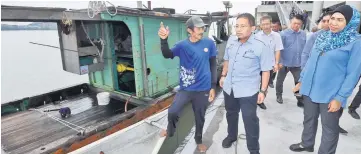  ??  ?? A fisherman (left) chats with Irmohizam who is leading an entourage to inspect the progress of LKIM Tanjung Bako Fishery Complex.