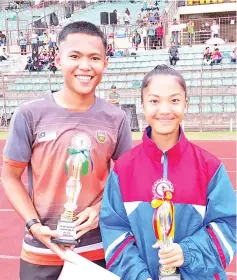  ??  ?? Alvin and Chlestie are all smiles after winning the Sportsman and Sportswoma­n awards at the closing ceremony of the 50th MSSS Track and Field Meet at the Likas Stadium, yesterday.