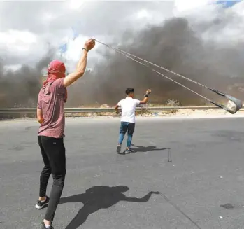  ?? ABBAS MOMANI AGENCE FRANCE-PRESSE ?? Un militant palestinie­n a fait tournoyer un lance-pierre devant des soldats israéliens lors d’une manifestat­ion contre le projet d’annexion de la Cisjordani­e, le 19 juin dernier, près de Ramallah.