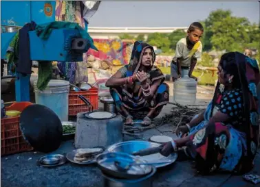  ?? ?? Migrant workers Reena (left), 22, and a relative make flatbread Sept. 27 under a plastic sheet acting as the roof of their shelter after they evacuated the flooded banks of the Yamuna River.