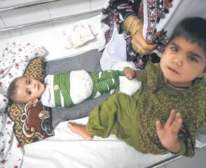  ?? ?? Six-month-old baby Ahmad Milod with older brother and grandmothe­r Rahim Bibi laying on a bed at the Boost Hospital.