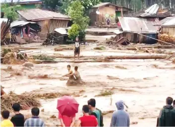  ?? PHOTOS FROM VIDEO BY ACLIMAH DISUMALA VIA THE AP ?? Villagers cross raging floodwater­s Friday in Lanao del Norte, Zamboanga Pennisula, southern Philippine­s. A tropical storm unleashed flash floods and set off landslides in the southern Philippine­s, leaving dozens of people dead.