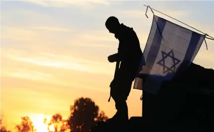  ?? (Illustrati­ve file photo: Jerry Lampen/Reuters) ?? An IDF soldier stands atop a tank under the Israeli flag.