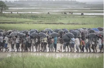  ?? — AFP photo ?? File photo shows Rohingya Muslim refugees waiting in line under the rain during a food distributi­on at Nayapara refugee camp in Bangladesh’s Ukhia district.