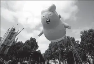  ?? The Associated Press ?? PARLIAMENT SQUARE: A six-meter high cartoon baby blimp representi­ng U.S. President Donald Trump is flown as a protest against his visit on Friday in Parliament Square in London, England. Trump was making his first trip to Britain as president after a tense summit with NATO leaders in Brussels and on the heels of ruptures in British Prime Minister Theresa May’s government because of the crisis over Britain’s exit from the European Union.