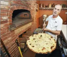  ?? CATHERINE AVALONE / HEARST CONNECTICU­T MEDIA ?? Pizza chef Nicky Mexhuani pulls a clam pizza from the brick oven at Viron Rondo Osteria in Cheshire.