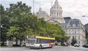  ?? KENNETH K. LAM/BALTIMORE SUN ?? Baltimore’s bus system, which includes LocalLink 80, seen passing City Hall, was revamped a year ago in an effort to improve service.