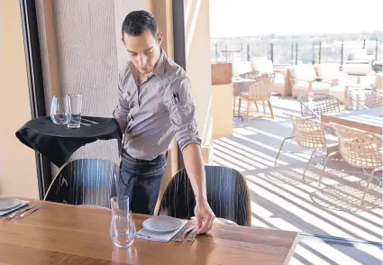  ?? MARLA BROSE/JOURNAL ?? Matthew Christie sets a table at a Hotel Chaco restaurant. While hospitalit­y-related jobs have been on the upswing in New Mexico, growth in the state’s overall private sector has been muted.