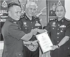  ??  ?? Merbin (right) hands over duty to Douglas (left) as the new district police chief, witnessed by Malek (centre).