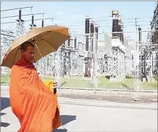  ?? HONG MENEA ?? A monk walks past an electrical power plant in Phnom Penh’s Russey Keo district in early 2014.