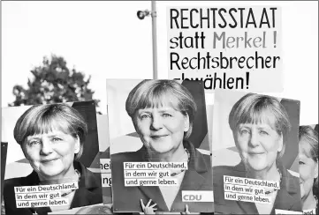  ??  ?? People hold a poster reading ‘Constituti­onal state instead of Merkel’ during a protest at an election rally in Dillingen, Germany. — Reuters photo