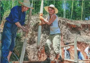  ?? LUO GUANGYAO / CHINA NEWS SERVICE GUANGDONG ?? A French volunteer learns how to build rammed-earth outer walls from a villager in Jiulong village, Fujian province.