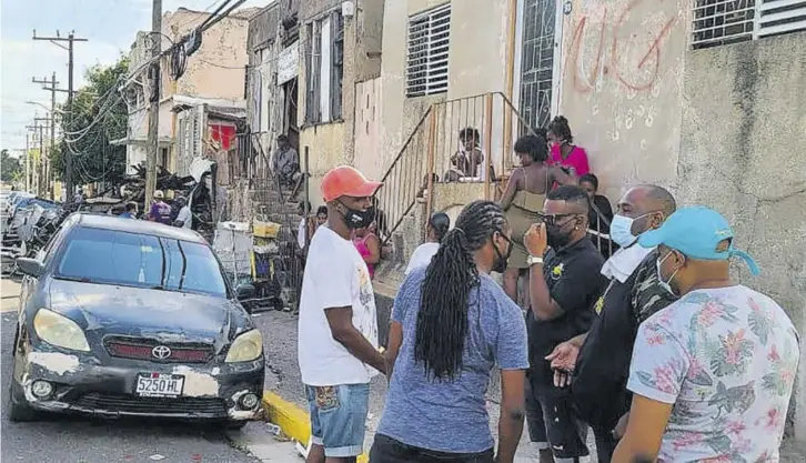  ??  ?? Producer Romaine “Luigi” Brown (second right), principal of Luigi Society label, converses with his team before distributi­ng meals, masks and toiletries in downtown Kingston on Christmas Day.