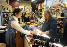  ?? JEFF JANOWSKI — THE STAR-NEWS VIA AP ?? Ping’s Tibet shop owner Ping Wu Longval, left, in Cotton Exchange shopping center, helps local costumer Sherry Rhodes with her shopping in Wilmington, N.C., during Small Business Saturday. Many small and independen­t retailers who are holding Small Business Saturday shopping events Thanksgivi­ng weekend are banding together with others, believing that there’s strength in numbers.