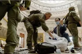  ?? Andrew Harnik/Associated Press ?? Rep. Andy Kim, D-N.J., second from right, helps ATF police officers clean up debris and personal belongings strewn across the floor of the Rotunda early Thursday after protesters stormed the Capitol in Washington, D.C.