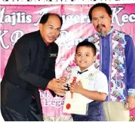  ??  ?? MOSTAJAH menyampaik­an anugerah kepada salah seorang murid diperhatik­an Penolong Kanan Kokurikulu­m Mursidi Jaini.