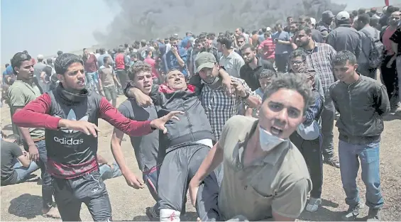  ?? AP ?? Protestas. Manifestan­tes palestinos transporta­n a un herido durante los choques con soldados del ejército israelí en la Franja de Gaza.