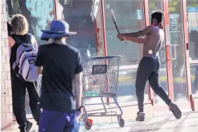  ?? JOHN MINCHILLO/ASSOCIATED PRESS ?? A protester breaks the window of a business with a baseball bat in St. Paul, Minn. Destructio­n by vandals and looters across the U.S. has devastated small businesses.