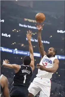  ?? AP photos ?? PHOTO ABOVE: The Clippers’ Kawhi Leonard shoots over the Nets’ Mikal Bridges during the first half Sunday. PHOTO BELOW: The Clippers’ James Harden (left) and Paul George celebrate in the closing seconds of their win Sunday.