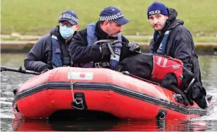  ?? ?? Scouring: Police take a sniffer dog on to a pond at Clapham Common