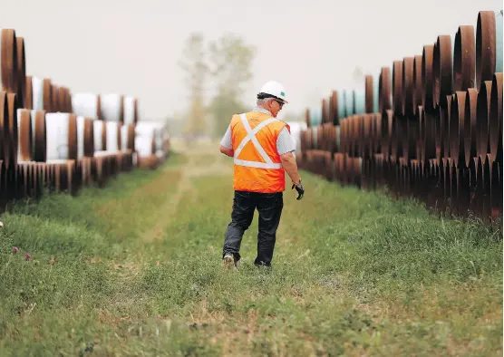  ?? JOHN WOODS/THE CANADIAN PRESS ?? An Enbridge employee walks through a oil pipe storage site west of Morden, Man. New pipeline export capacity is expected in late 2019 when Enbridge Inc.’s Line 3 replacemen­t project is forecast to be completed. Energy companies are counting on relief from significan­t oil price differenti­als due to a supply glut and lack of pipelines.