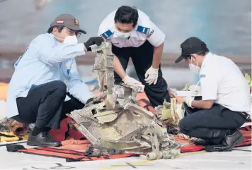  ?? DITA ALANGKARA/AP ?? Indonesia plane crash: Investigat­ors inspect pieces of downed Sriwijaya Air flight SJ-182 Thursday in Jakarta, Indonesia. Authoritie­s ended the search for the wreckage of the plane that nosedived Jan. 9 into the Java Sea, killing all 62 people on board. A limited search for the missing memory unit from the cockpit voice recorder will continue.