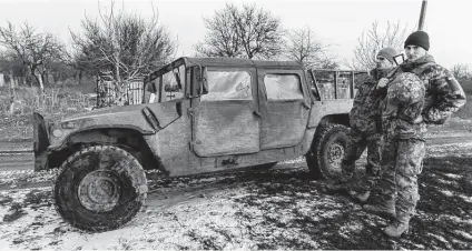  ?? Andriy Dubchak / Associated Press ?? Ukrainian soldiers stand near their Humvee at the line of separation from pro-russian rebels. Russian President Vladimir Putin is a modern-day Peter the Great out to restore the glory of the old USSR; but mostly, he’s just looking to keep himself in power.