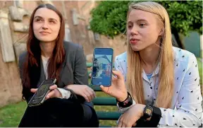  ?? AP ?? Kateryna Prokopenko, wife of Denys Prokopenko, commander of the Azov regiment, right, and Yulia Fedosiuk, wife of Arseny Fedosiuk, another member of Azov regiment, show photograph­s on their phones of their husbands, who are defending the Azovstal steel plant in Mariupol. The women are calling for any evacuation of civilians to also include soldiers.