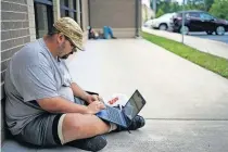  ?? [BRYAN WOOLSTON/ THE ASSOCIATED PRESS] ?? Barlow Mitchell sits outside the Lee County Public Library while using the public WI-FI on July 29 in Beattyvill­e, Ky.