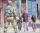  ?? WASEEM ANDRABI/HT ?? A Kashmiri man, along with his children, walks past paramilita­ry soldiers during restrictio­n in the downtown area of Srinagar on Sunday.