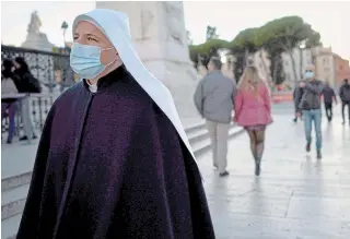  ?? ANDREW MEDICHINI THE ASSOCIATED PRESS ?? A nun wearing a mask walks in Rome on Tuesday. Italian Premier Giuseppe Conte says the aim of Italy’s new anti-virus restrictio­ns is to head off another generalize­d lockdown.