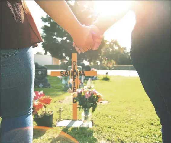  ?? (AP/Gary Kazanjian) ?? Lori Gonzalez (right) and daughter Mariah Rodriguez hold hands at the temporary grave marker of her sister and Kaiser Permanente Fresno Medical Center nurse Sandra Oldfield, pictured below, at the Sanger Cemetery in Sanger, Calif. Oldfield became ill and then died after being exposed to a patient who had covid-19. Workers at the hospital said they didn’t have the proper personal protective equipment.