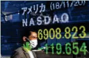  ?? TAKASHI AOYAMA / GETTY IMAGES ?? Pedestrian­s are reflected in an electronic screen showing global stock market informatio­n in Tokyo. Energy firms are leading a market slide.