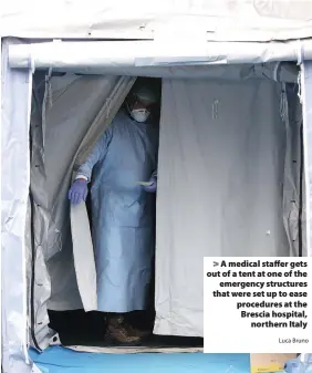  ?? Luca Bruno ?? > A medical staffer gets out of a tent at one of the emergency structures that were set up to ease procedures at the Brescia hospital, northern Italy