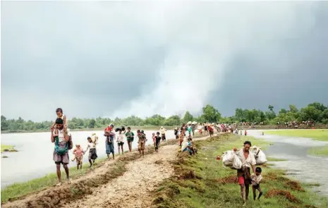  ?? Credit ADAM DEAN FOR THE NEW YORK TIMES ?? Rohingya refugees this month near the Naf River, which separates Myanmar and Bangladesh. Villages in Myanmar burned in the background.