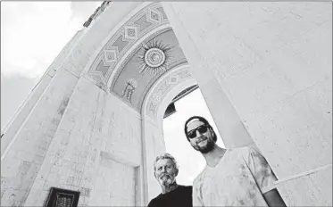  ?? LUIS SINCO/LOS ANGELES TIMES ?? Mick Rosien, left, and Nick Rosien stand under a mural at the Los Angeles Coliseum painted by Mick’s father, Heinz, in 1969.