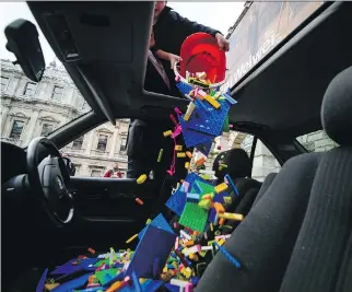  ?? LEON NEAL/AFP/GETTY IMAGES ?? Lego bricks are poured through the sunroof of a BMW, used as a receptacle for donations of Lego bricks in the courtyard of the Royal Academy in central London on Friday.