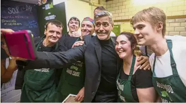  ??  ?? Say cheese: A file photo of Clooney taking a wefie with homeless employees of the Social Bite cafe in Edinburgh in November 2015. — EPA