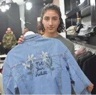  ?? NASSER SHIYOUKHI/AP ?? Yasmeen Mjalli displays a jacket she designed with the slogan “Not Your Habibti (darling),” a retort for cat calls, at a clothing store in the West Bank city of Ramallah. The 21-year-old is the driving force behind a nascent #MeToo movement in the West...