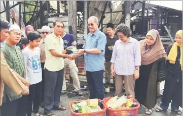  ??  ?? Minister of Natural Resources and Environmen­t Datuk Seri Dr Wan Junaidi Tuanku Jaafar (front, fourth right) hands over disaster relief aid to Jarni Abang Ossen, a resident of Kampung Tabuan Hilir in Kuching. Jarni is among the villagers whose houses...