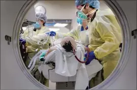  ?? Nelvin C. Cepeda The San Diego Union- Tribune ?? SCOTT BOOTH, right, a CT technician at UC San Diego Health in La Jolla, positions a COVID- 19 patient for a CT scan before he goes to the intensive care unit.