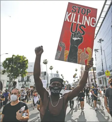  ?? (File Photo/AP/Marcio Jose Sanchez) ?? A protester carries a sign in the Hollywood area of Los Angeles during June 1 demonstrat­ions over the death of George Floyd. Black people are facing a combinatio­n of stressors hitting simultaneo­usly: isolation during the pandemic, a shortage of mental health care providers and racial trauma inflicted by repeated police killings of Black people. Black people suffer disproport­ionately from covid-19 and have seen soaring rates in youth suicide attempts.