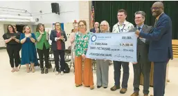  ?? PAUL W. GILLESPIE/STAFF ?? Bodkin Elementary School teacher Bradley Absher, center, holds a big check with other officials. Absher was awarded a surprise $25,000 Milken Educator Award during an assembly on Thursday at the school.